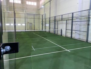Pista de pádel indoor con césped verde